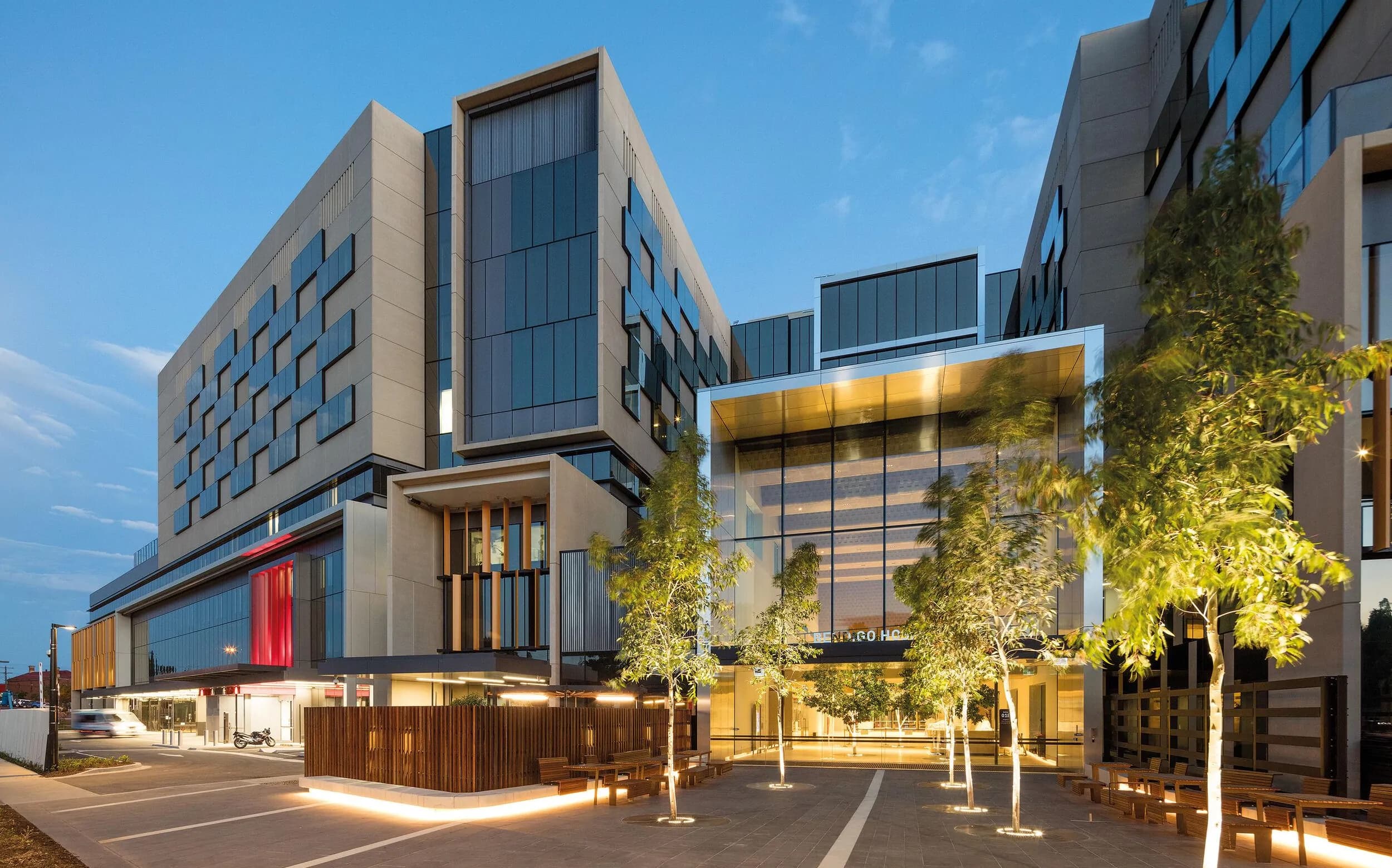 Modern hospital building and landscaped courtyard lit at dusk